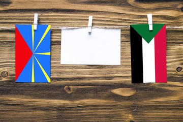 Hanging flags of Reunion and Sudan attached to rope with clothes pins with copy space on white note...