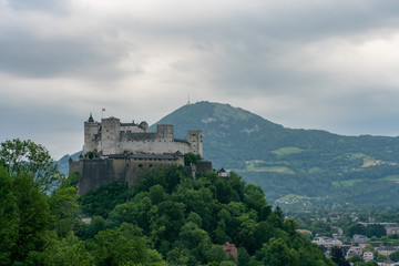 View of the Hohensalzburg fortress and mountains on a cloudy day. Location: Salzburg, Austria.