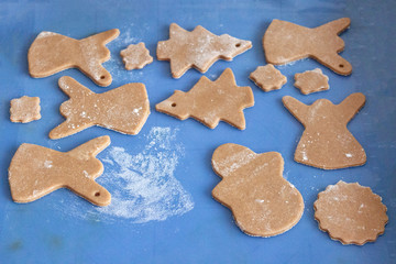 Gingerbread cookie dough on a blue board in the shape of Christmas heroes