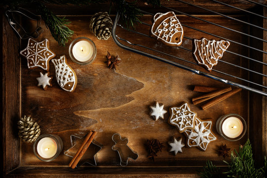 Gingerbread, Burning Candles And Cookie Cutters On A Dark Wooden Tray, Christmas Arrangement With Copy Space In The Middle, Flat Lay, High Angle View From Above