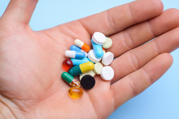 Middle aged man holds medicine pills in hand in bathroom before taking them