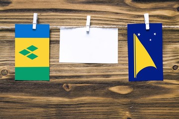 Hanging flags of Saint Vincent And The Grenadines and Tokelau attached to rope with clothes pins...