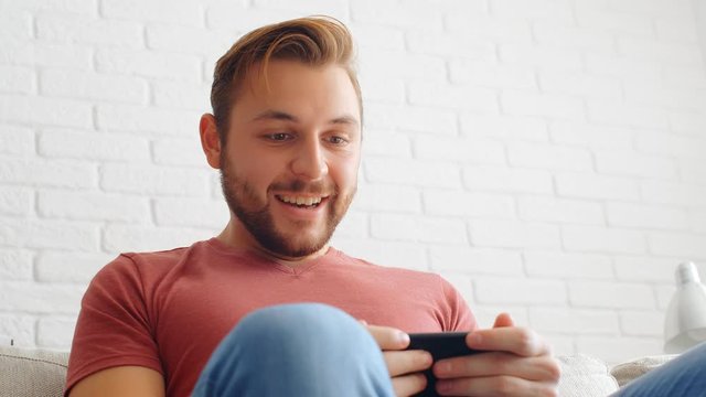 Sports Fan Reaction Concept - Excited sports fan watching his favourite team/player on smartphone at home, 4k slow motion