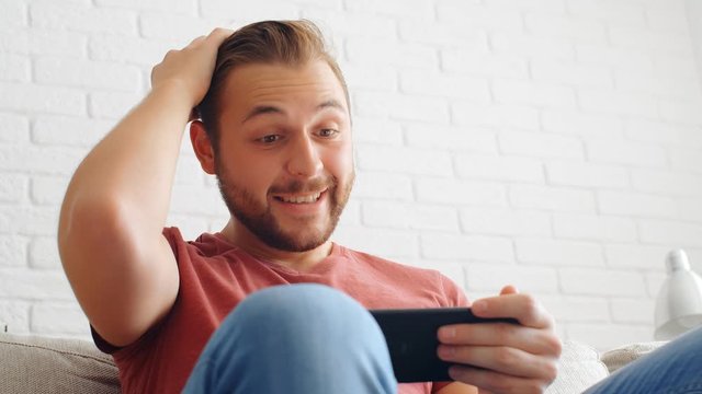 Sports Fan Reaction Concept - Excited sports fan watching his favourite team/player on smartphone at home, 4k slow motion
