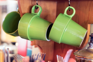 Two green coffee mugs hanged in a kitchen, natural light