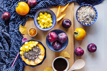 Fototapeta na wymiar Breakfast bowl with oat, yogurt, mango, persimmon and chia, top view