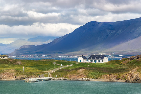 The Videy Island and an old white guest house viewed from the coastline of Reykjavik, Iceland