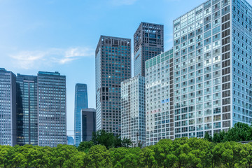 green trees front of modern glass office building.