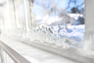 Ice forming on the inside glass of a drafty window in winter