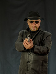 A man in black clothes, a black leather coat, hat. Ganster with a cigar Mauser system pistol. Mafiosi in black glasses on a dark background. Severe, strong, stylish, impressive, dangerous, unfriendly,