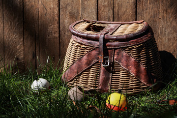 Fishing bobbers with vintage Creel basket outside in the grass - obrazy, fototapety, plakaty