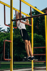 Fototapeta premium Muscular man doing pull-ups on horizontal bar in urban park