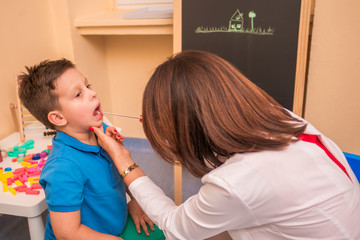 Female Pediatrician check's the throat and mouth of a young cute boy.