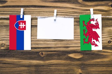 Hanging flags of Slovakia and Wales attached to rope with clothes pins with copy space on white...