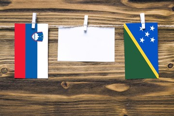 Hanging flags of Slovenia and Solomon Islands attached to rope with clothes pins with copy space on...