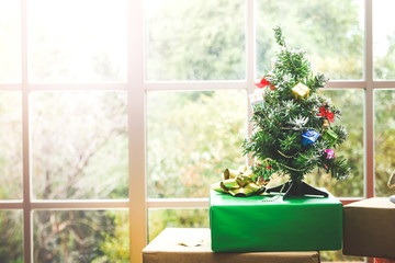 Happy new year concept of bauble decoration hanging on a Christmas tree. With many gifts placed in the room by the window. Leave a space to write a message.