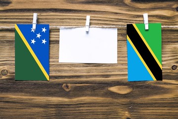 Hanging flags of Solomon Islands and Tanzania attached to rope with clothes pins with copy space on...