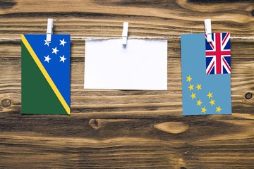 Hanging flags of Solomon Islands and Tuvalu attached to rope with clothes pins with copy space on...