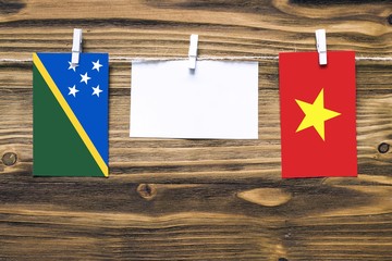 Hanging flags of Solomon Islands and Vietnam attached to rope with clothes pins with copy space on...