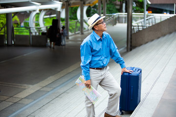 Fototapeta premium Portrait of happy senior mature man of travelers with luggage and map. Enjoying travel and happy tourism concept.