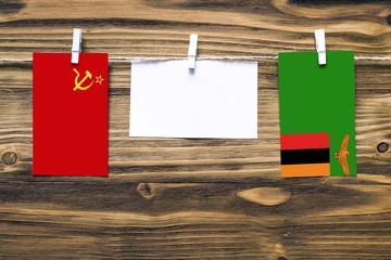 Hanging flags of Soviet Union and Zambia attached to rope with clothes pins with copy space on...