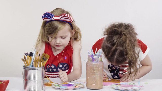 Little girls are painting on canvas on July 4th party.