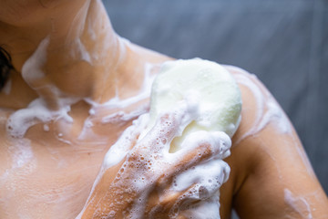 woman shower with body scrub sponge