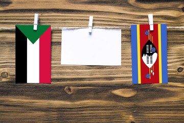 Hanging flags of Sudan and Swaziland attached to rope with clothes pins with copy space on white...