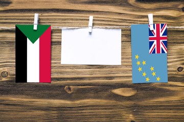Hanging flags of Sudan and Tuvalu attached to rope with clothes pins with copy space on white note...