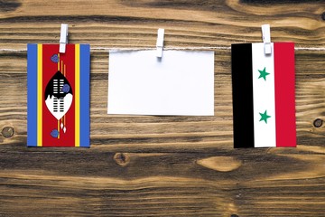 Hanging flags of Swaziland and Syria attached to rope with clothes pins with copy space on white...