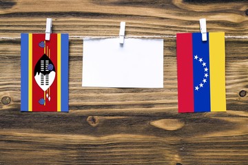 Hanging flags of Swaziland and Venezuela attached to rope with clothes pins with copy space on...