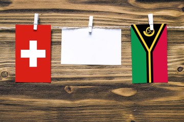 Hanging flags of Switzerland and Vanuatu attached to rope with clothes pins with copy space on...