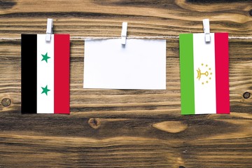 Hanging flags of Syria and Tajikistan attached to rope with clothes pins with copy space on white...