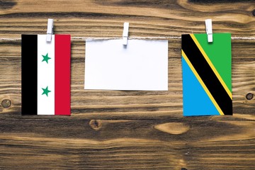 Hanging flags of Syria and Tanzania attached to rope with clothes pins with copy space on white...