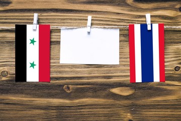Hanging flags of Syria and Thailand attached to rope with clothes pins with copy space on white...