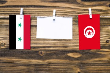 Hanging flags of Syria and Tunisia attached to rope with clothes pins with copy space on white note...