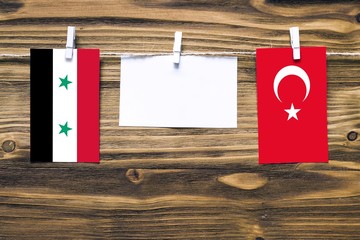 Hanging flags of Syria and Turkey attached to rope with clothes pins with copy space on white note...