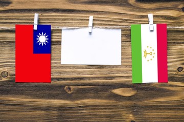 Hanging flags of Taiwan and Tajikistan attached to rope with clothes pins with copy space on white...