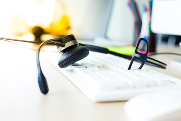 Closeup of headphone on computer keyboard at call center service office space. Customer service tools concept.