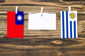 Hanging flags of Taiwan and Uruguay attached to rope with clothes pins with copy space on white...