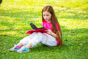 Fototapeta premium Cute Little Blond Girl Reading Book Outside on Grass