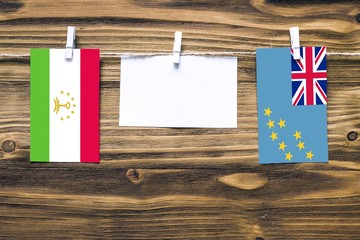 Hanging flags of Tajikistan and Tuvalu attached to rope with clothes pins with copy space on white...