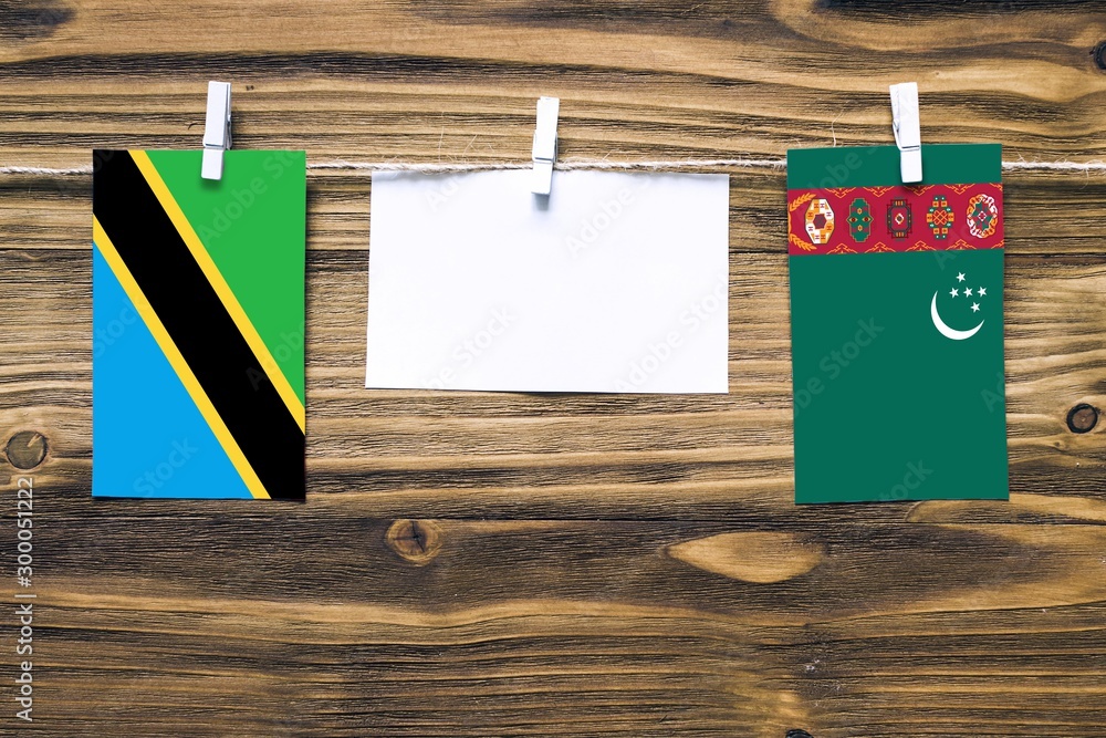 Wall mural Hanging flags of Tanzania and Turkmenistan attached to rope with clothes pins with copy space on white note paper on wooden background.Diplomatic relations between countries. - Wall murals