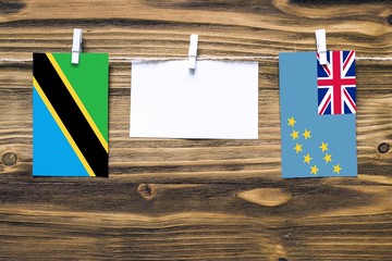 Hanging flags of Tanzania and Tuvalu attached to rope with clothes pins with copy space on white...