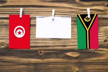 Hanging flags of Tunisia and Vanuatu attached to rope with clothes pins with copy space on white...