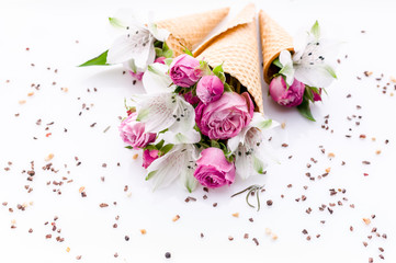 Bouquets of flowers in waffle cones on a chocolate chip pattern. Rose and alstrameria on a white background. Theme for greeting cards or wedding invitations.