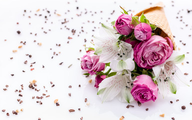 Bouquet of flowers in a waffle cone on a chocolate chip pattern. Rose and alstrameria on a white background. Theme for greeting cards or wedding invitations. Copy space