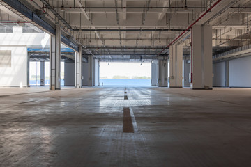 Backlit perspective view of interior space of concrete building warehouse