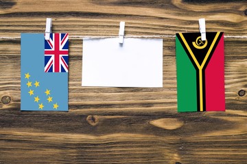 Hanging flags of Tuvalu and Vanuatu attached to rope with clothes pins with copy space on white...
