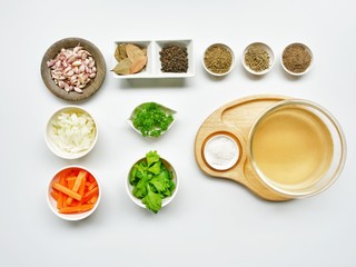 Ingredients homemade stock water included garlic, carrots, celery ,onions, parsley, time, rosemary, oregano, bayleav, salt, black pepper. on white background. 